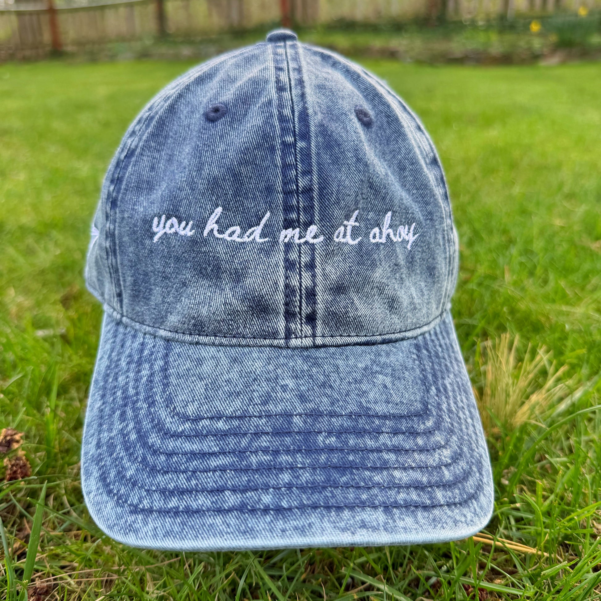 Blue denim cap with 'you had me at ahoy' text on grass