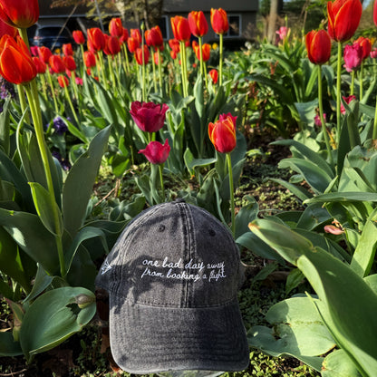 "One bad day away from booking a flight" Funny hat for travel lovers - amongst flowers