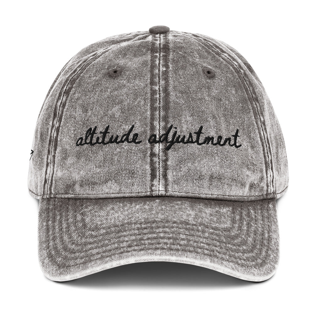 Vintage wash grey travel themed hat with words "altitude adjustment" on it