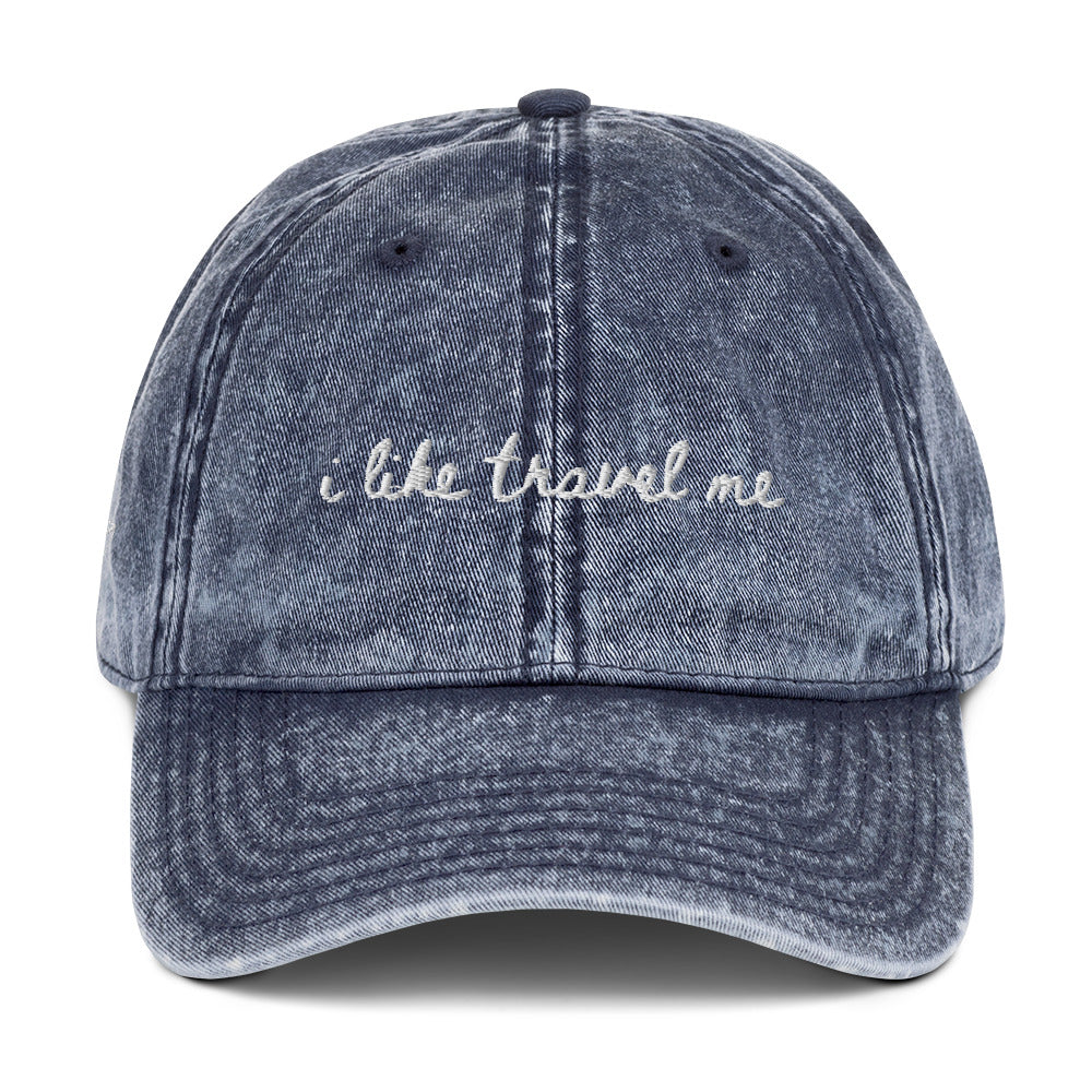 Vintage wash blue travel hat with the words "i like travel me" embroidered on it