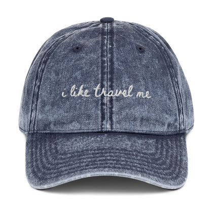 Vintage wash blue travel hat with the words "i like travel me" embroidered on it